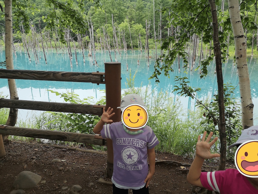 美瑛・青い池の前で手を振る子どもたち