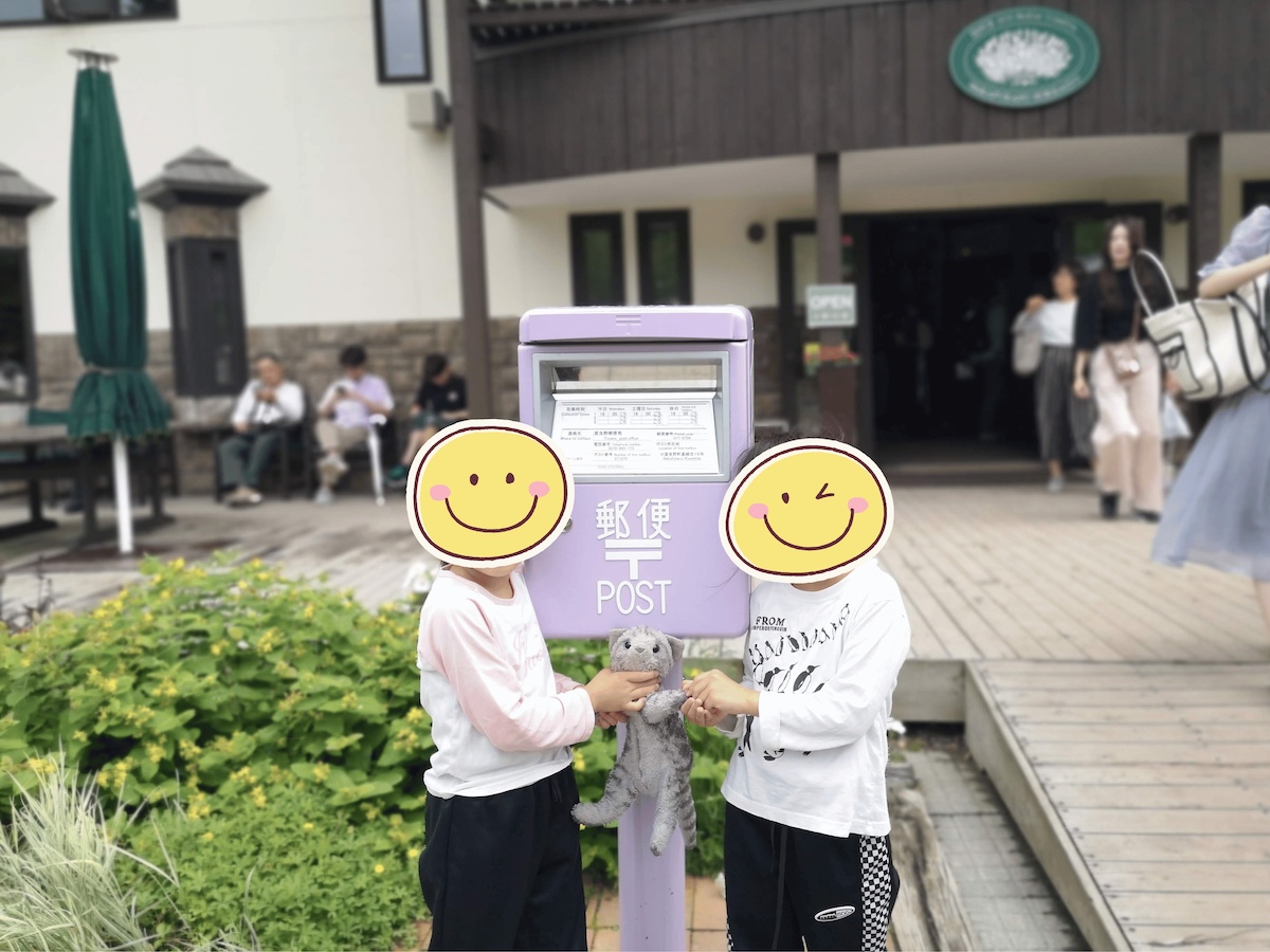 ファーム富田のラベンダー色のポストの前で笑顔の子ども2人